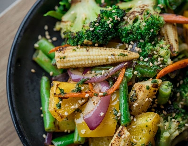 A vibrant mix of grilled vegetables on a black plate, perfect for healthy eating.